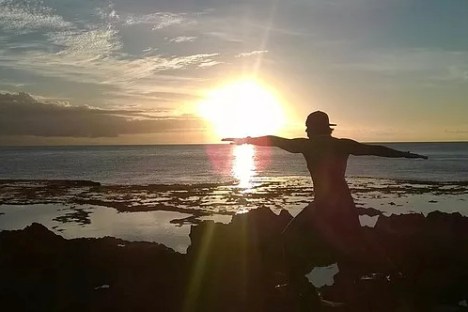 a man standing on a beach in front of a sunset